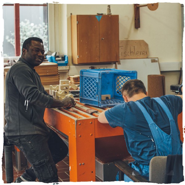 Zwei Mitarbeiter in der Holzwerkstatt am Tisch sitzend und arbeitend